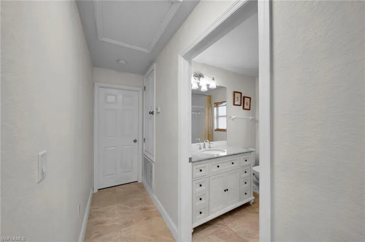 Corridor featuring baseboards, attic access, and a textured wall