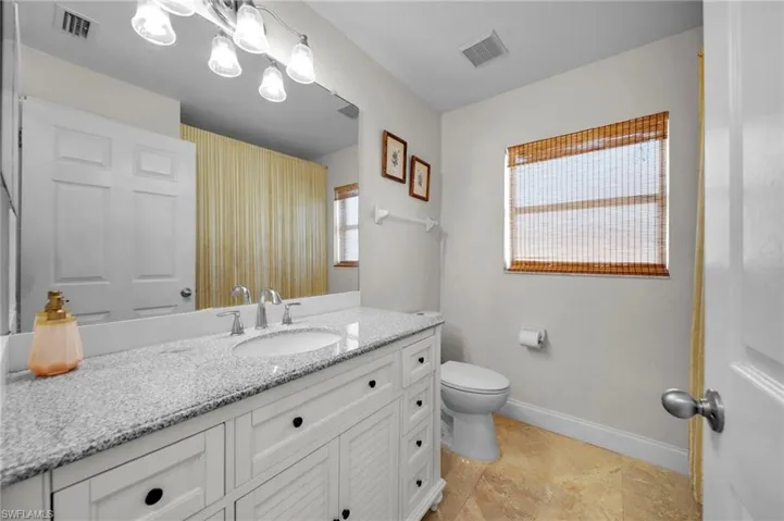 Bathroom featuring vanity, visible vents, baseboards, and toilet