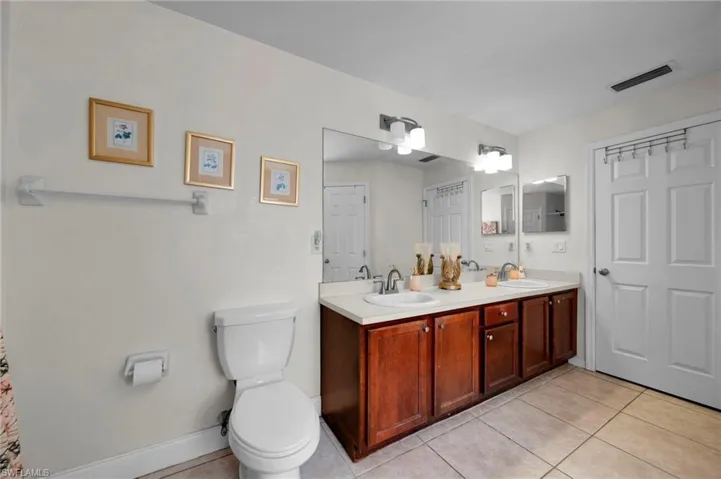 Bathroom with toilet, tile patterned floors, a sink, and visible vents