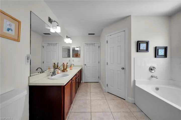 Full bath featuring a garden tub, visible vents, toilet, a sink, and tile patterned floors