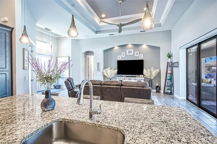 Kitchen with light stone counters, hanging light fixtures, sink, and light hardwood / wood-style floors