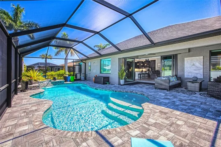 View of swimming pool with an outdoor living space, glass enclosure, a patio area, ceiling fan, and pool water feature