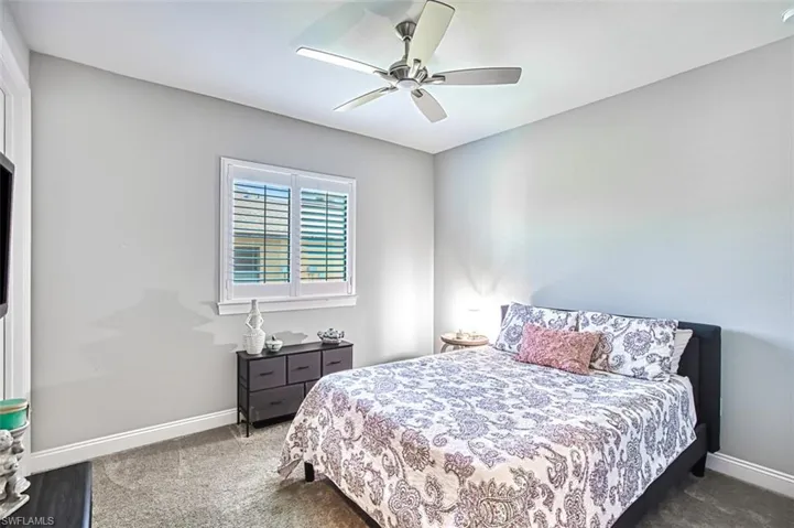 Bedroom with ceiling fan and dark carpet