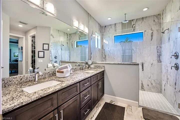 Bathroom featuring dual bowl vanity, tile flooring, and tiled shower