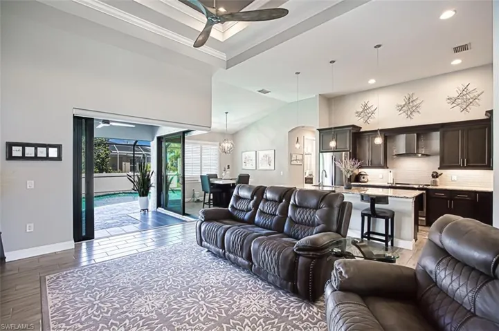 Living room featuring a towering ceiling, hardwood / wood-style floors, sink, and ceiling fan