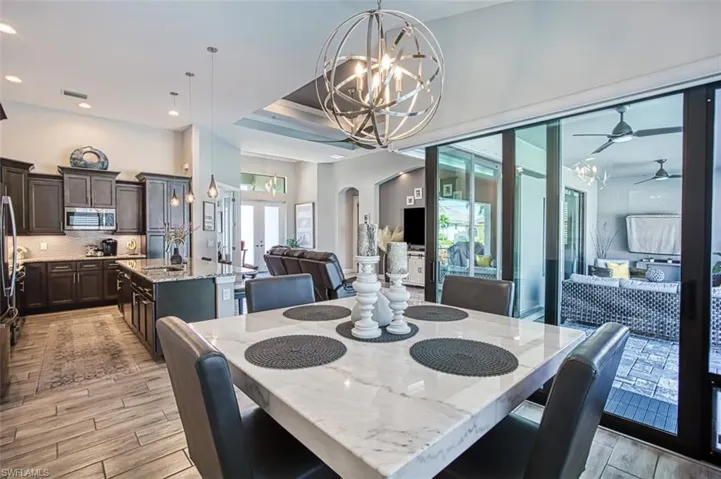 Dining space with a tray ceiling, ceiling fan with notable chandelier, a healthy amount of sunlight, and sink