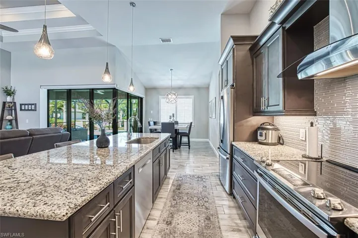 Kitchen featuring an island with sink, sink, tasteful backsplash, and plenty of natural light