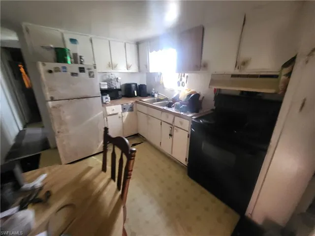Kitchen with white appliances, white cabinetry, sink, and exhaust hood