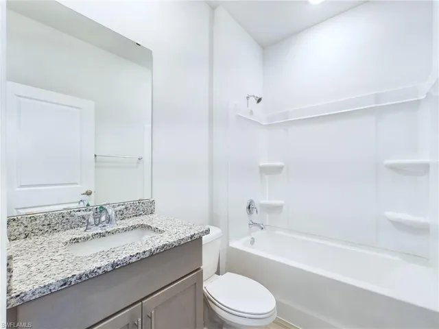Full bathroom featuring toilet,  shower combination, and vanity