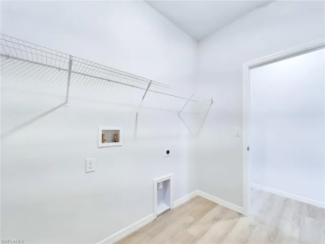 Clothes washing area with light hardwood / wood-style floors, hookup for a washing machine, and hookup for an electric dryer