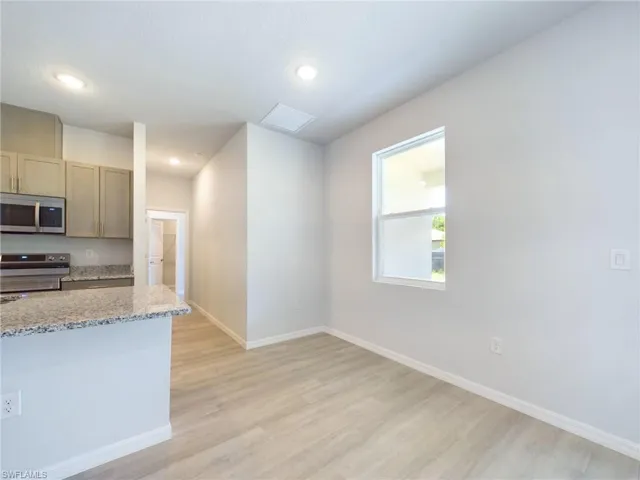 Kitchen with light wood-type flooring, stove, and light stone countertops
