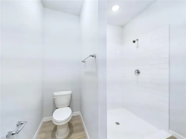 Bathroom featuring tiled shower, wood-type flooring, and toilet