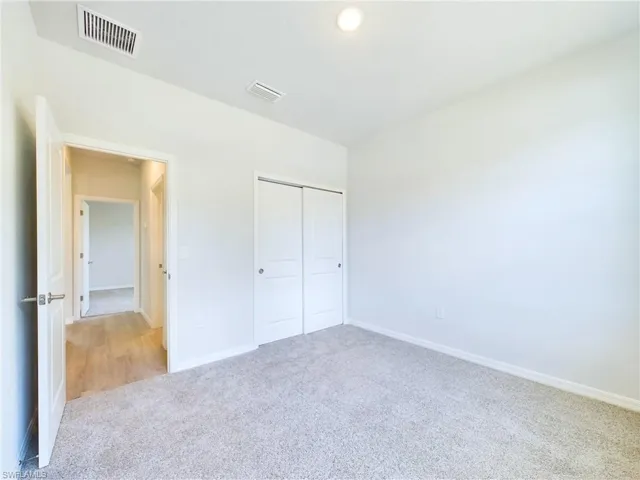 Unfurnished bedroom featuring a closet and light colored carpet