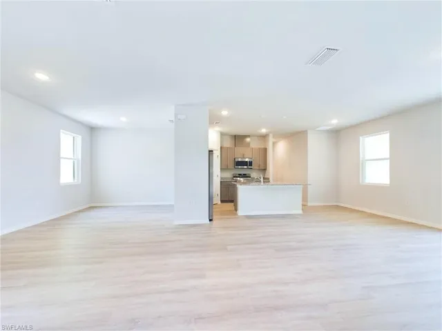 Unfurnished living room with a wealth of natural light, light hardwood / wood-style flooring, and sink