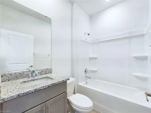 Full bathroom featuring toilet, washtub / shower combination, and vanity