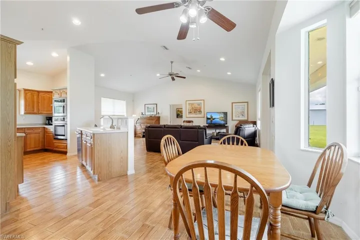Dining space featuring ceiling fan, light hardwood / wood-style flooring, and vaulted ceiling