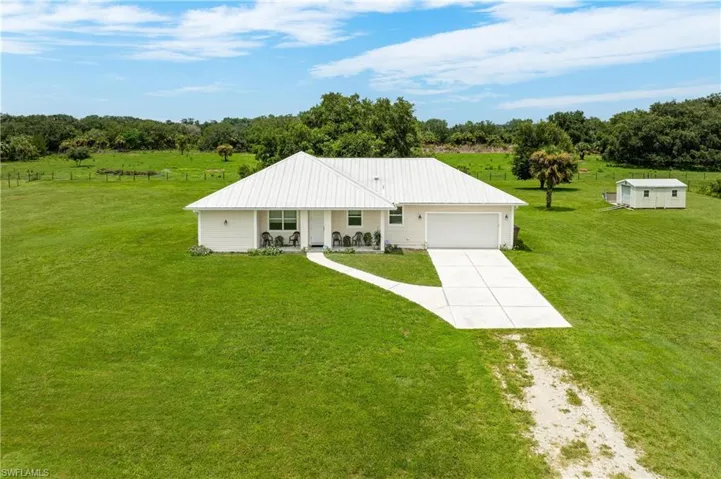 Single story home featuring a front lawn, a garage, and a rural view