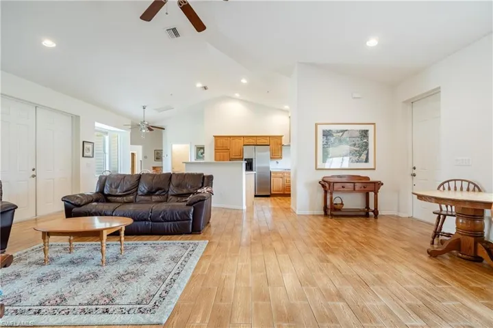 Living room with ceiling fan, high vaulted ceiling, and light hardwood / wood-style floors