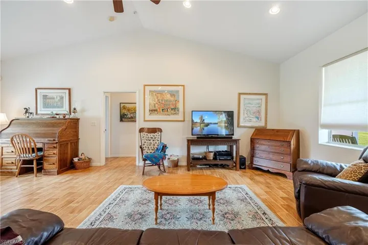 Living room featuring ceiling fan, light hardwood / wood-style flooring, and lofted ceiling