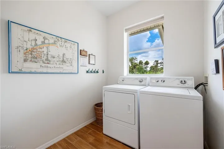 Clothes washing area featuring washing machine and clothes dryer and hardwood / wood-style flooring