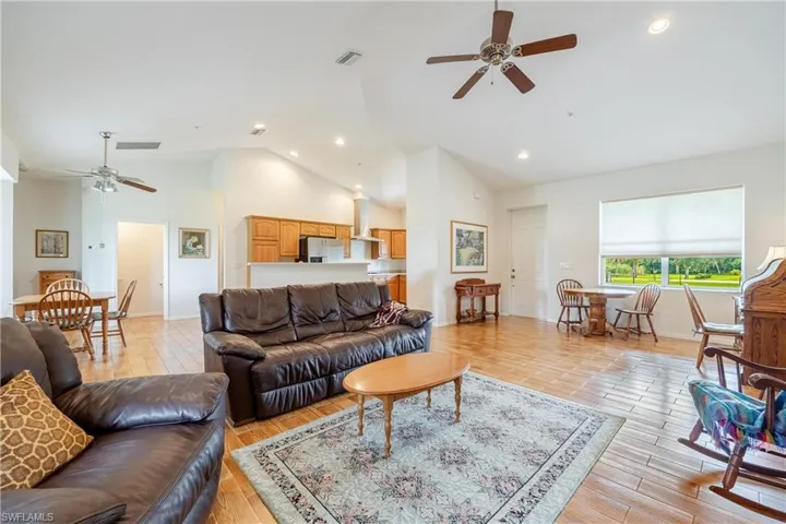 Living room featuring ceiling fan, high vaulted ceiling, and light hardwood / wood-style floors