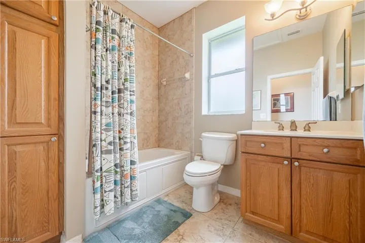 Full bathroom with shower / bath combo with shower curtain, vanity, tile patterned flooring, and toilet