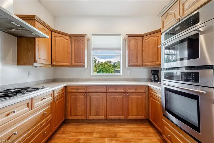 Kitchen with wall chimney range hood, gas cooktop, and double oven