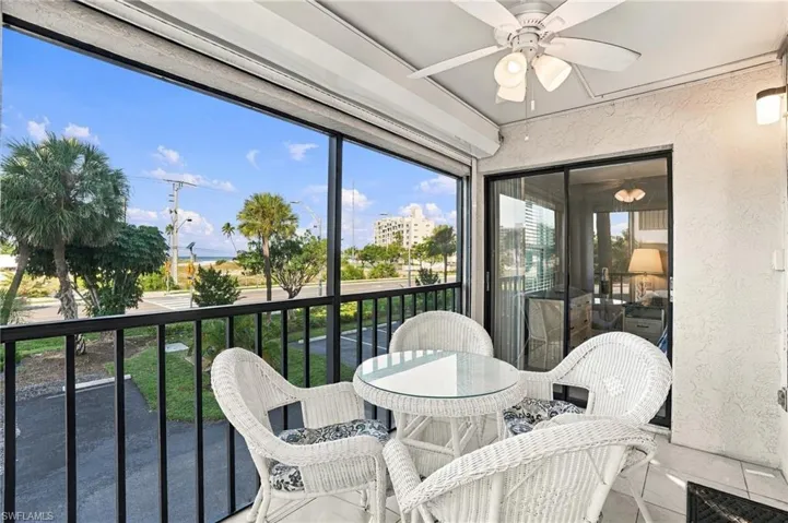 Screened-in balcony featuring tile flooring, a ceiling fan with integrated lighting, and metal railings