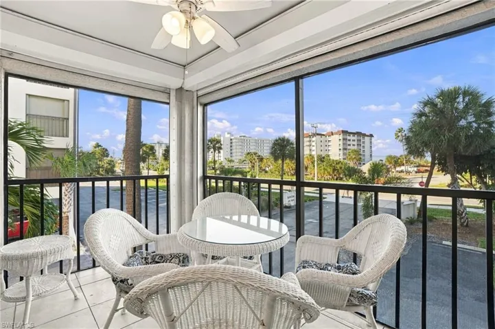 Screened-in balcony featuring tile flooring, a ceiling fan, and metal railings