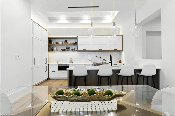 Kitchen with tasteful backsplash, a breakfast bar, light countertops, white cabinetry, and light wood finished floors