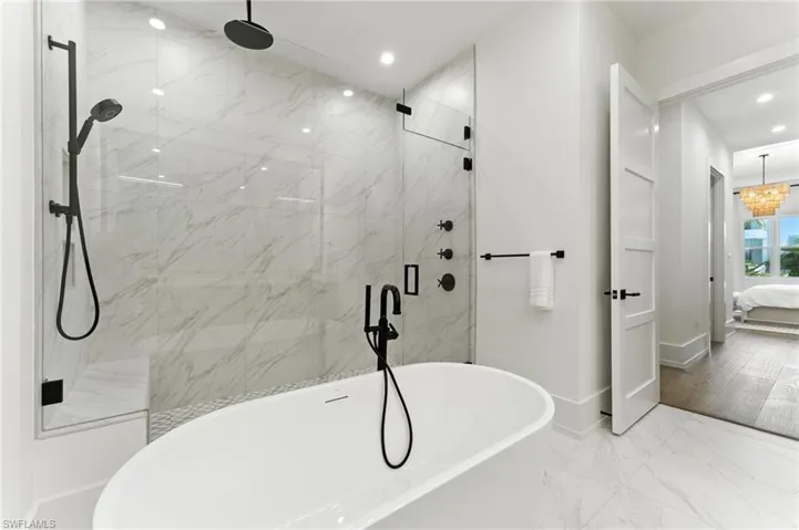 Ensuite bathroom featuring recessed lighting, a freestanding tub, a marble finish shower, and marble finish floors