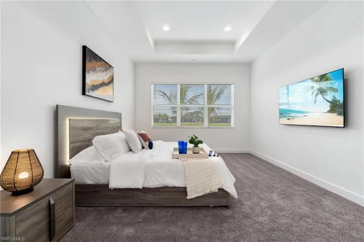 Bedroom with a raised ceiling and dark carpet