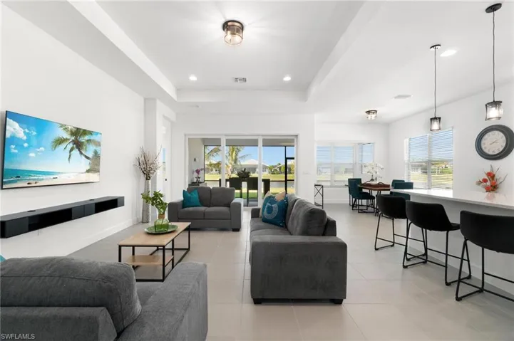 Living room with light tile patterned flooring, a tray ceiling, and a healthy amount of sunlight