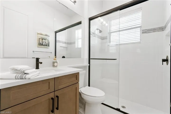 Bathroom featuring a shower with shower door, vanity, and toilet