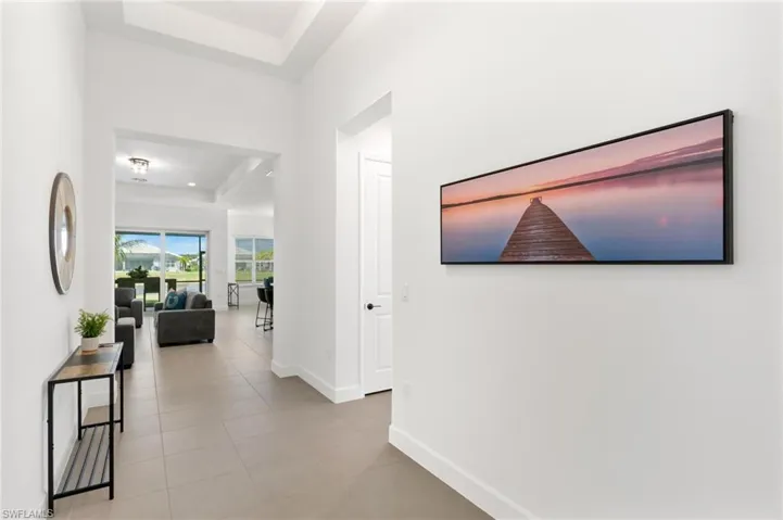 Hallway featuring a raised ceiling and light tile patterned floors