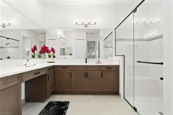 Bathroom featuring an enclosed shower, tile patterned flooring, and double sink vanity