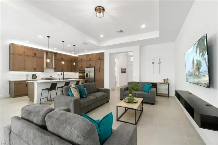 Living room with light tile patterned flooring, sink, and a tray ceiling