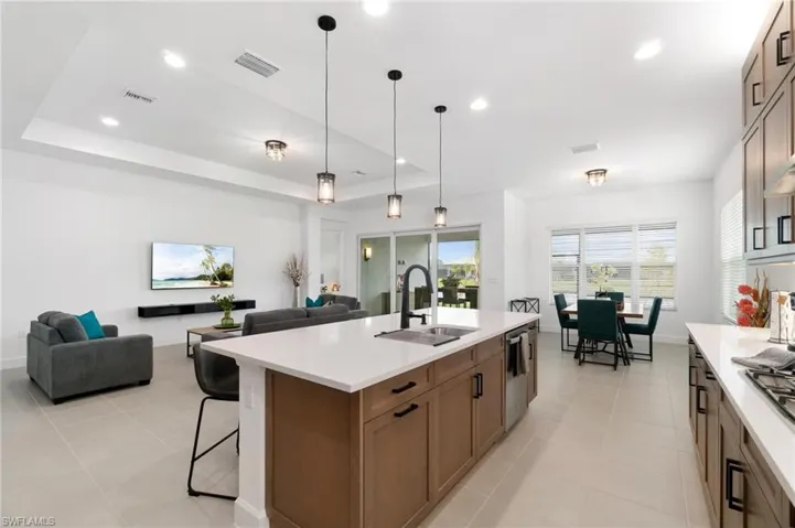 Kitchen featuring sink, a kitchen bar, an island with sink, and a tray ceiling