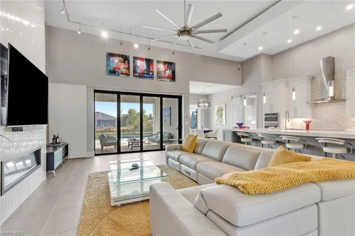 Living area featuring light tile patterned floors, a high ceiling, a ceiling fan, recessed lighting, and a chandelier