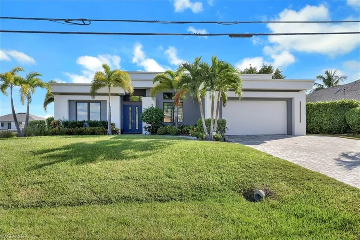 Contemporary home with a front lawn, decorative driveway, stucco siding, and a garage