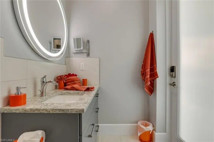 Half bath featuring tasteful backsplash, vanity, and light tile patterned floors