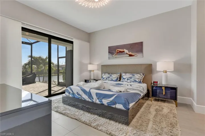 Bedroom featuring a water view, access to exterior, and light tile patterned floors