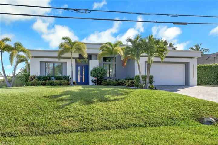 View of front of house featuring decorative driveway, a front yard, stucco siding, and an attached garage