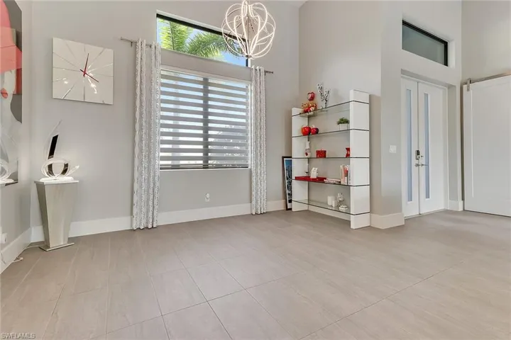 Unfurnished dining area with a high ceiling, a chandelier, light tile patterned floors, and french doors