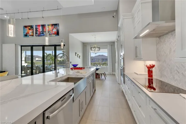 Kitchen with white cabinets, wall chimney range hood, and dishwasher