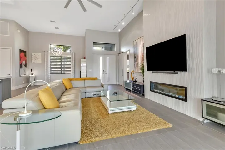 Living room with a fireplace, ceiling fan, and track lighting