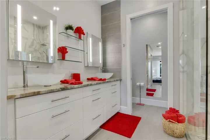 Full bath featuring double vanity and a marble finish shower