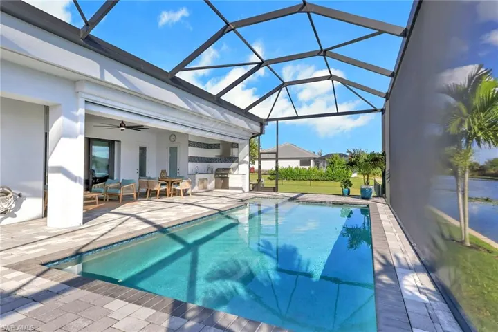 Outdoor pool featuring a patio, ceiling fan, a lanai, a sunroom, and exterior kitchen