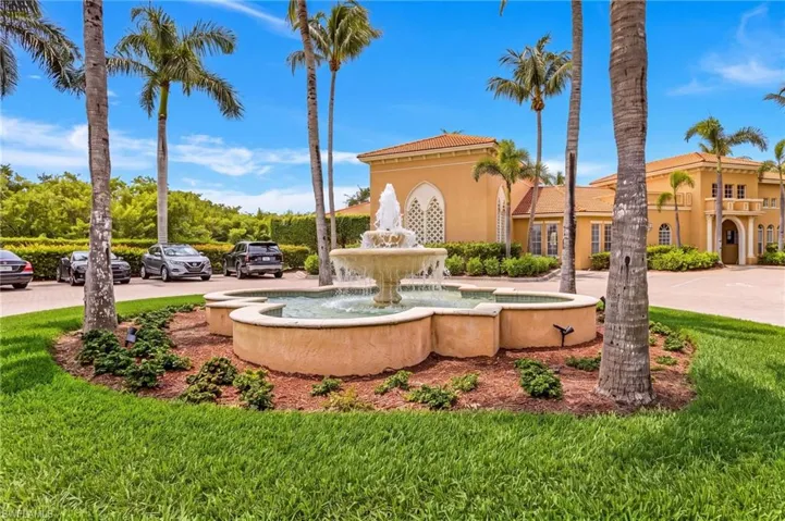 Multi-tiered fountain feature, surrounded by manicured landscaping and mature palm trees