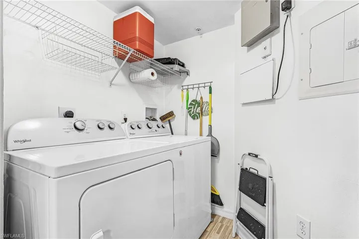 Utility area with a washer and dryer, wire shelving, and wood-finish flooring